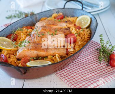 Délicieux repas de famille avec du saumon frit et des pâtes dans une délicieuse sauce tomate. Banque D'Images