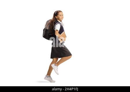 Fille dans un uniforme d'école avec un sac à dos saut à l'école isolée sur fond blanc Banque D'Images