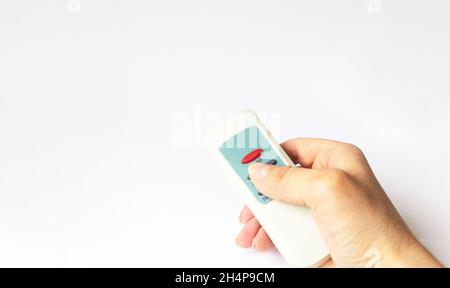 Une main femelle tient une télécommande sur un fond blanc. Banque D'Images