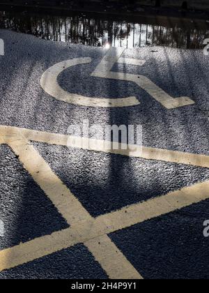 Ici, nous voyons des motifs d'ombres projetées par une clôture, un pont de chemin de fer et des panneaux sur une place de stationnement pour handicapés dans le parking de la gare de Radley.C'est la pandémie, s Banque D'Images