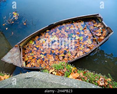 Une vue surréaliste - un bateau à rames en contrebas rempli de feuilles d'automne mortes ; vu par St Helens Wharf, un endroit de beauté réputé sur la Tamise à Abingdon, Banque D'Images