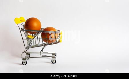 Deux œufs de poulet dans un petit panier.Mini chariot avec œufs sur fond blanc.Isoler sur fond blanc. Banque D'Images