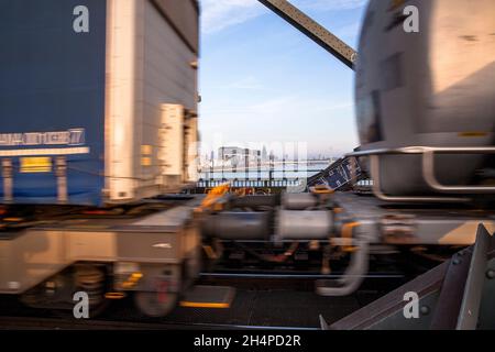 Vue à travers l'écart entre deux wagons d'un train de marchandises passant sur le Suedbruecke au port de Rheinau avec les Crane Houses et à la cathédrale Banque D'Images