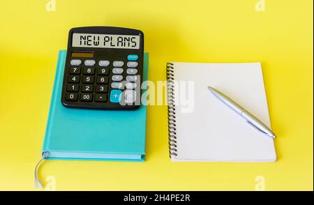 Calculatrice avec NOUVELLE inscription DE PLAN sur fond jaune, concept argent, finance et business.Bloc-notes à l'aide d'un stylet, placez-le pour le texte. Banque D'Images