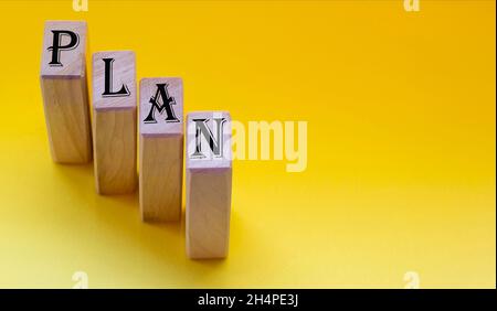 lettres de l'alphabet sur des blocs de bois se tenant sur fond jaune.Concept de planification d'entreprise. Banque D'Images