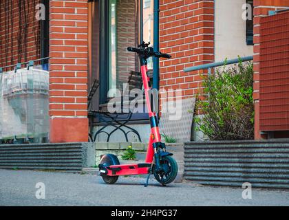 Location de Kick-scooter électrique sur le trottoir de la rue devant le bâtiment mural en briques.E-scooter pour le partage public dans le centre-ville européen. Banque D'Images