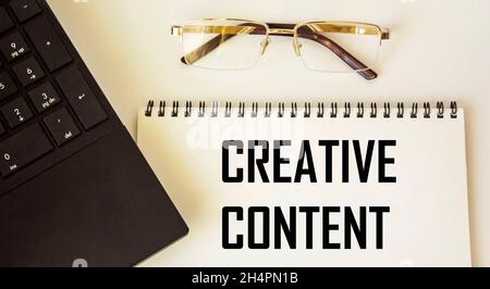 Le contexte CRÉATIF du texte est écrit sur le bloc-notes.Près de l'ordinateur portable et des lunettes Banque D'Images