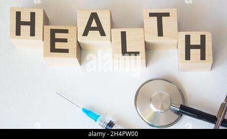 sur les cubes en bois, la santé du texte est proche d'une injection et d'un stéthoscope Banque D'Images