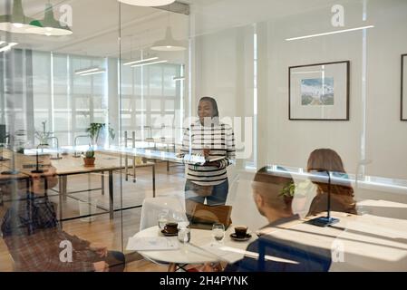 Homme d'affaires parlant à des collègues assis autour d'une table dans un bureau Banque D'Images