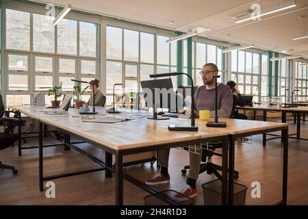 Jeunes hommes d'affaires et collègues concentrés travaillant dans un bureau à plan ouvert Banque D'Images