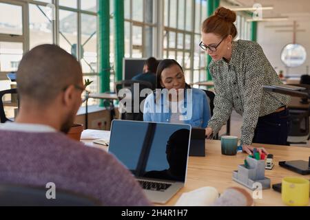 Deux femmes d'affaires diverses travaillant sur une tablette dans un bureau Banque D'Images