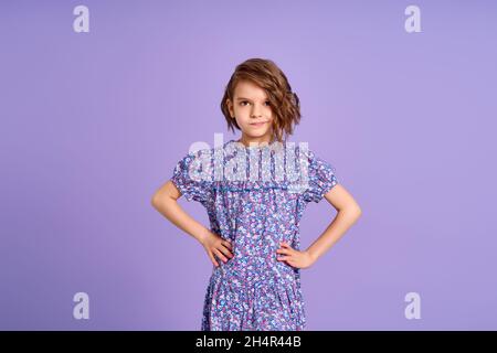 Sceptique petite fille maure portant dans la robe lilas tandis que se tient sur fond violet studio Banque D'Images