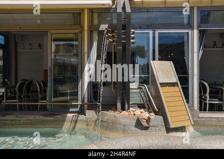 Une fontaine moderne en pierre et en acier en face d'un café dans le village de pêcheurs de San Vincenzo, Livourne, Toscane, Italie Banque D'Images