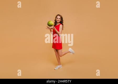 Belle fille dans une robe jette un petit melon d'eau. Banque D'Images