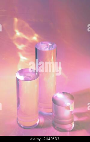 trois podiums en verre transparent sur fond rose pastel Banque D'Images