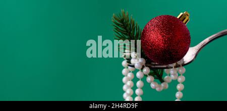 Bannière avec gros plan sur les décorations de Noël sur une fourchette de perles blanches, branche d'arbre de Noël et boule de Noël rouge sur fond vert. Concept de nourriture festive pour noël ou nouvel an. Espace pour les copies Banque D'Images