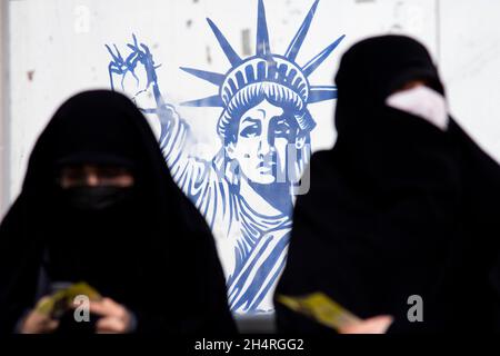 Téhéran, Iran.04e novembre 2021.Deux femmes s'assoient devant un graffiti anti-américain lors d'un rassemblement devant l'ancienne ambassade des États-Unis commémorant l'anniversaire de sa saisie de 1979 à Téhéran, en Iran, le jeudi 4 novembre 2021.La prise de pouvoir de l'ambassade a déclenché une crise d'otages de 444 jours et une rupture des relations diplomatiques qui se poursuit jusqu'à ce jour.(Photo de Sobhan Farajvan/Pacific Press/Sipa USA) crédit: SIPA USA/Alay Live News Banque D'Images