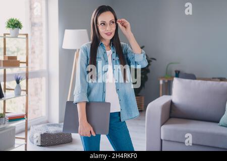 Photo de rêve heureux positif mature femme porte des lunettes look imagine indépendant ordinateur portable à l'intérieur de la maison Banque D'Images