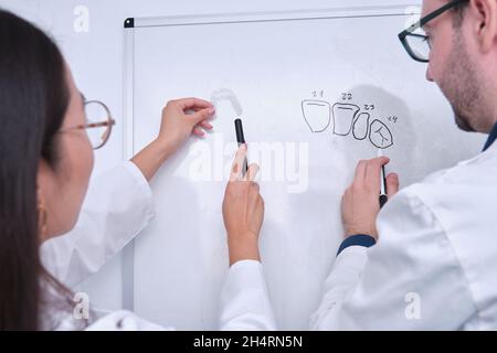 Deux chercheurs odontologues étudient l'anatomie dentaire sur un tableau blanc. Banque D'Images