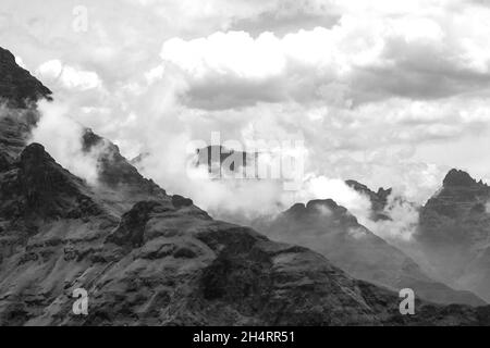 Les nuages se rassemblent en noir et blanc entre les hauts pics de basalte déchiquetés des montagnes du Drakensberg, qui font partie du grand escarpement de l'Afrique du Sud. Banque D'Images