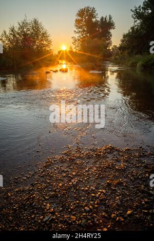 Photo verticale des rayons du soleil au lever du soleil sur la rivière Banque D'Images