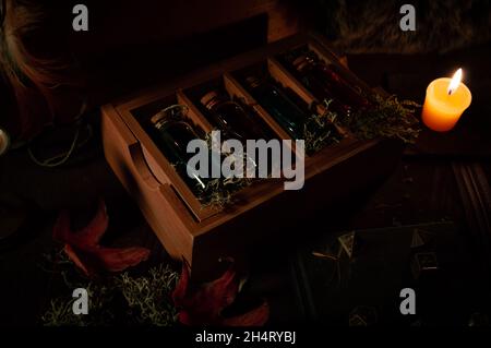 Une scène sombre avec des attributs magiques focalisés sur une boîte en bois avec des bouteilles de verre remplies de liquide bleu et rouge. Banque D'Images