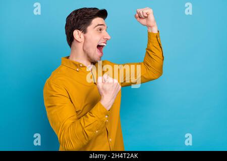 Profil photo de gai champion Guy célébrer la victoire vide espace porter chemise jaune isolé couleur bleu fond Banque D'Images