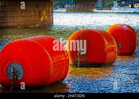 Bouées Ahoy!- Une ligne de trois bouées flottantes orange sur la Tamise dans le centre-ville de Londres. Banque D'Images