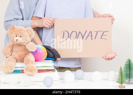 Don de Noël, concept de charité de vacances.Les mains des enfants et des femmes tiennent un morceau de carton brun avec l'inscription donner.Les bénévoles collectent des vêtements Banque D'Images