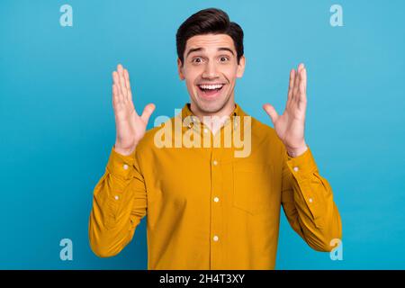 Photo de l'excitée surprise gars ouvert bouche lever les paumes porter chemise jaune isolé couleur bleu arrière-plan Banque D'Images