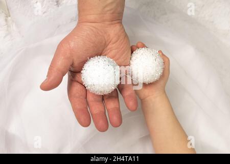 Père et fille tiennent deux boules de Noël décoratives blanches décorant l'arbre de Noël.Unité et famille du nouvel an et de la veille de Noël Banque D'Images