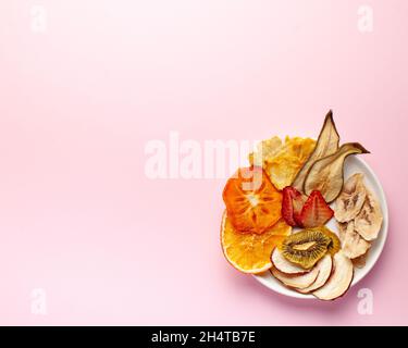 Croustilles de fruits séchées sur fond rose. Le concept d'en-cas sain sans sucre, dessert pour les végétariens. Copier l'espace. Banque D'Images