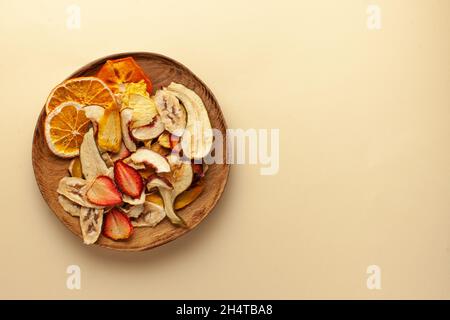 Copeaux de fruits séchés sur une assiette en bois. Le concept d'une collation saine sans sucre, dessert pour les végétariens. Copier l'espace. Banque D'Images