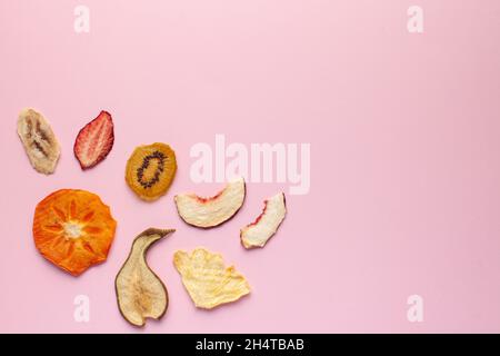 Croustilles de fruits séchées sur fond rose. Le concept d'en-cas sain sans sucre, dessert pour les végétariens. Copier l'espace. Banque D'Images