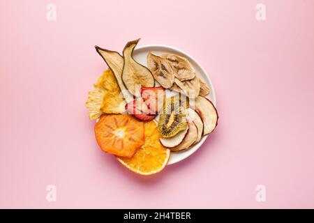 Croustilles de fruits séchées sur fond rose. Le concept d'en-cas sain sans sucre, dessert pour les végétariens. Copier l'espace. Banque D'Images