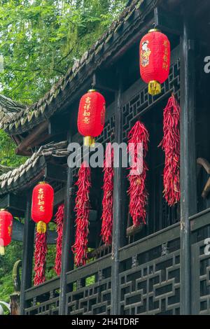 Des brins de piments rouges et de lanternes chinoises dans un bâtiment traditionnel en bois du parc forestier national de Zhangjiajie, Hunan, Chine. Banque D'Images