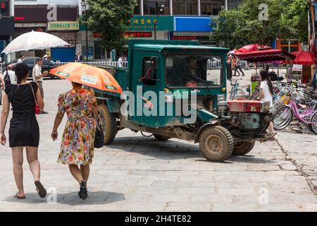 Les gens marchent à bord d'un véhicule utilitaire chinois dans la rue à Yangshuo, en Chine. Banque D'Images