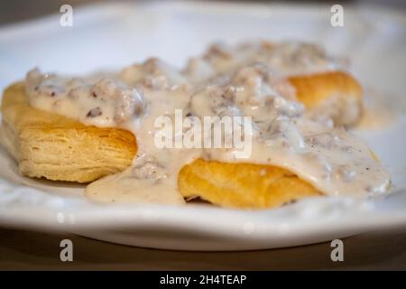 Sauce au lait assaisonnée avec saucisse de porc sur biscuits sur une assiette blanche. Banque D'Images