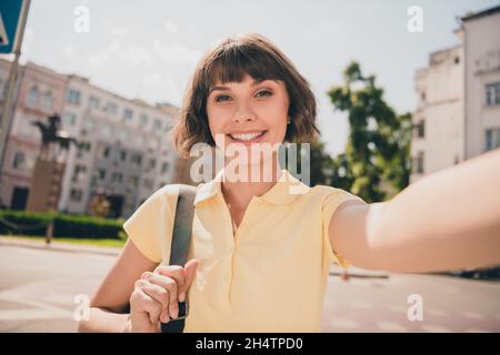 Photo de la belle femme brunette millénaire ne selfie porter un t-shirt jaune à l'extérieur du parc Banque D'Images