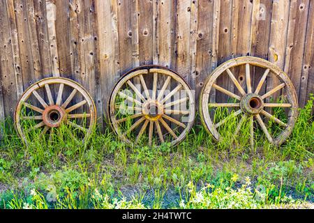 Trois vieilles roues de chariot en bois abîmé contre un mur de grange Banque D'Images