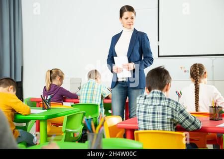 Enseignant contrôlant l'écriture des élèves de l'école primaire Banque D'Images