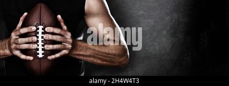 Joueur de football homme joueur tenant le football américain sur fond noir de texture de tableau noir avec espace de copie pour le texte ou le design.Bannière panoramique. Banque D'Images