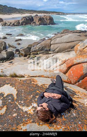 Femme couchée sur des rochers à Beerbarrel Beach Banque D'Images