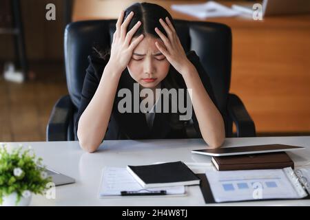 Les employés de l'entreprise se montrent ennuyés par un travail inachevé utilisant un ordinateur portable, des documents et des tablettes au travail. Banque D'Images