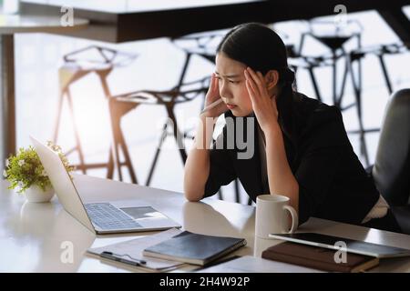 Les employés de l'entreprise se montrent ennuyés par un travail inachevé utilisant un ordinateur portable, des documents et des tablettes au travail. Banque D'Images