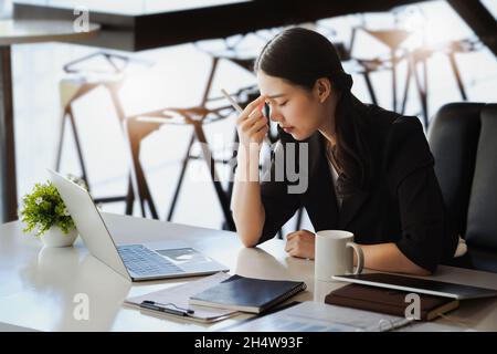 Les employés de l'entreprise se montrent ennuyés par un travail inachevé utilisant un ordinateur portable, des documents et des tablettes au travail. Banque D'Images