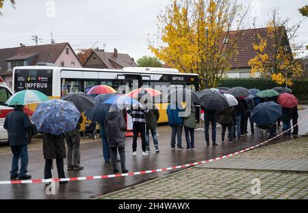 Notzingen, Allemagne.04e novembre 2021.Les gens attendent en ligne avec des parapluies devant un bus de vaccination.Credit: Marijan Murat/dpa/Alamy Live News Banque D'Images