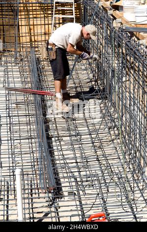 Un ouvrier de la construction a nouée les barres d'armature pour former la base d'une nouvelle piscine Banque D'Images