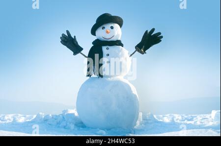 Bonhomme de neige avec chapeau et écharpe en hiver en plein air.Bonhomme de neige en hiver chapeau, écharpe et gants noirs.Noël ou fête de noël, espace de copie. Banque D'Images