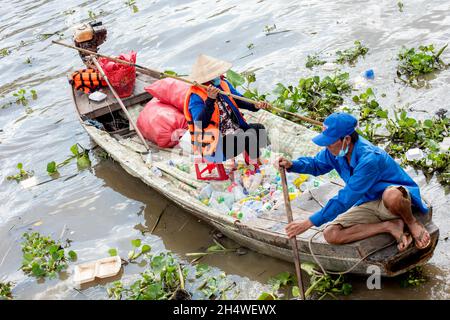 Les travailleurs pauvres ramassant des bouteilles en plastique qui polluent l'environnement sur le fleuve au Vietnam Banque D'Images